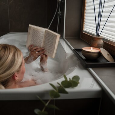 Eine junge Frau sitzt gemütlich in der Badewanne und genießt ein Buch | © Karin Pasterer