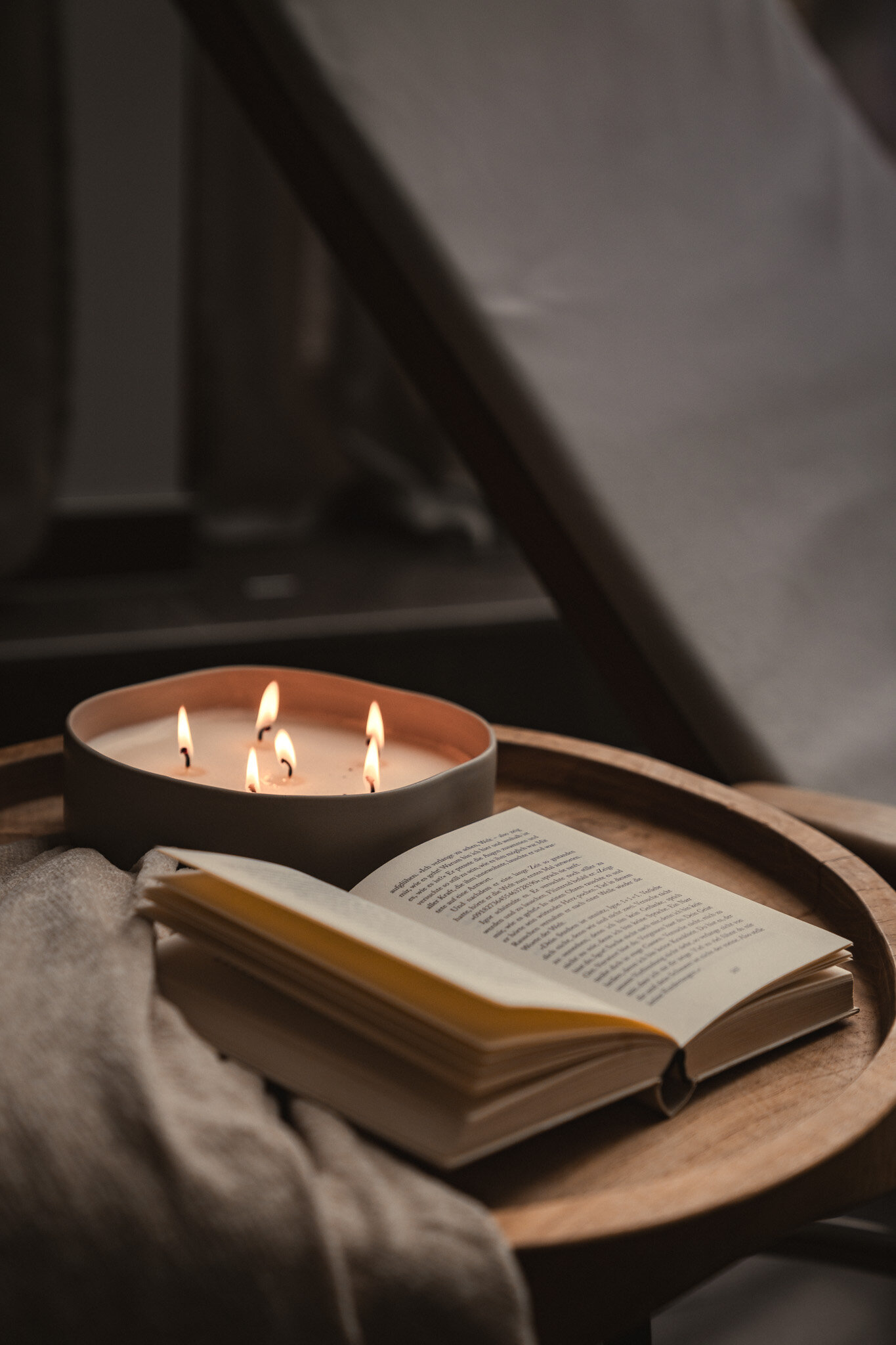 Nahaufnahme einer stimmungsvolle Kerze und einem offenen Buch auf einem Couchtisch | © Karin Pasterer