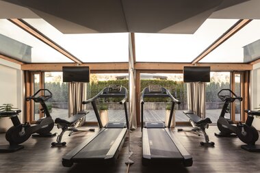 Gym mit Laufband, Räder und Bänken vor einem riesen Fenster | © Karin Pasterer